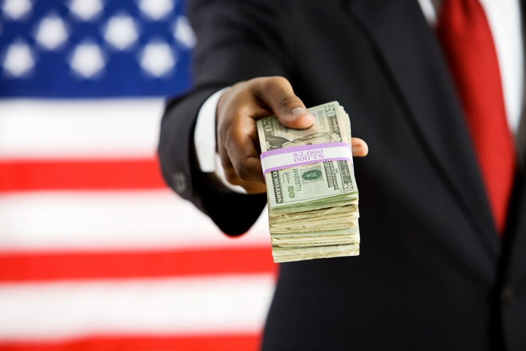 U.S. flag and man offering a wad of dollars